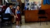 Una niña se prueba un uniforme escolar en una tienda de ropa reciclada en La Habana. (REUTERS/Alexandre Meneghini)