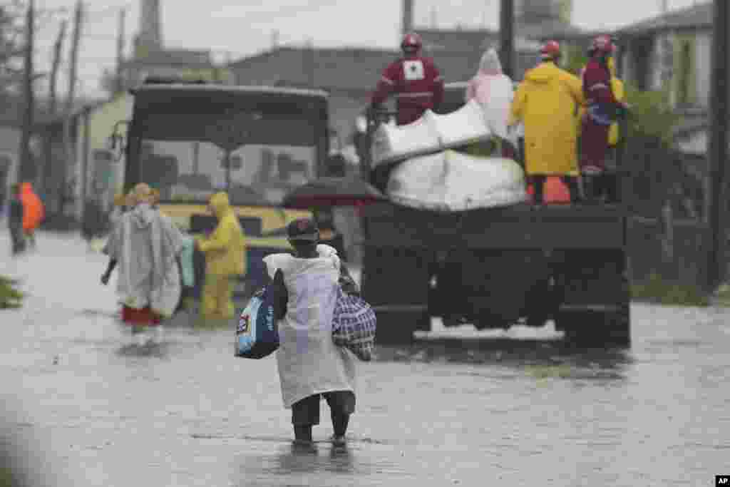 Residentes cruzan una calle inundada, en Batabanó, tras el paso de Idalia por el occidente cubano.