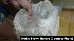 Una vecina muestra un pedazo de concreto desprendido del techo de su apartamento en un edificio de Antilla, Holguín, en peligro de derrumbe.