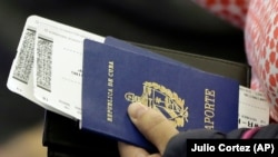 Una persona sostiene su pasaporte cubano antes de subir a un vuelo (Julio Cortez/AP)