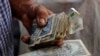 Un hombre sostiene pesos cubanos. REUTERS/Desmond Boylan