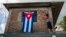 Una mujer cuelga una bandera cubana en su ventana. (JUAN BARRETO / AFP / Archivo)