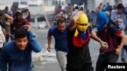 Manifestantes huyen durante un enfrentamiento con la fuerzas de seguridad durante una protesta en Caracas el 30 de abril de 2019.
