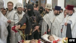 CRISIS EN SLAVIANSKUn guerrillero armado prorruso echa flores sobre los cuerpos de tres hombres durante el funeral celebrado en una iglesia ortodoxa de Slaviansk, Ucrania, el 22 de abril del 2014.