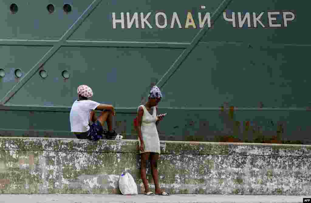 Personas permanecen frente al remolcador de rescate y salvamento Nikolai Chiker, parte del destacamento naval ruso que visita Cuba, tras su llegada al puerto de La Habana el 12 de junio de 2024. YAMIL LAGE / AFP