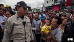 Un hombre con un niño en brazos grita consignas a un miembro de la Policía Nacional Bolivariana (PNB) durante una protesta para exigir alimentos en el sector popular Catia, en Caracas (Venezuela). Nuevos focos de protesta