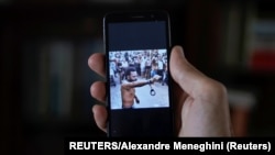 Un hombre que no quiso ser identificado muestra en su teléfono al rapero contestatario Maykel Castillo El Osorbo. (REUTERS/Alexandre Meneghini)