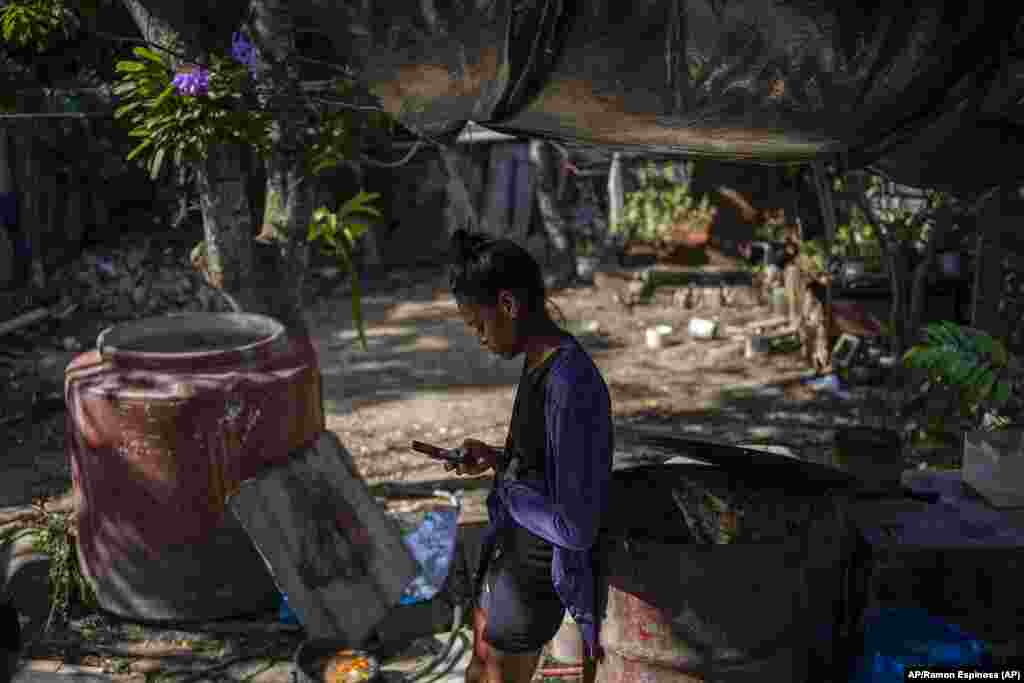 María Carla Milan Ramos, esposa de Yosney Emilio Román Rodríguez, detenido junto a sus dos hermanos, acusados de participar en las protestas contra el gobierno, mira su celular en el patio de su casa en La Guinera , Cuba.